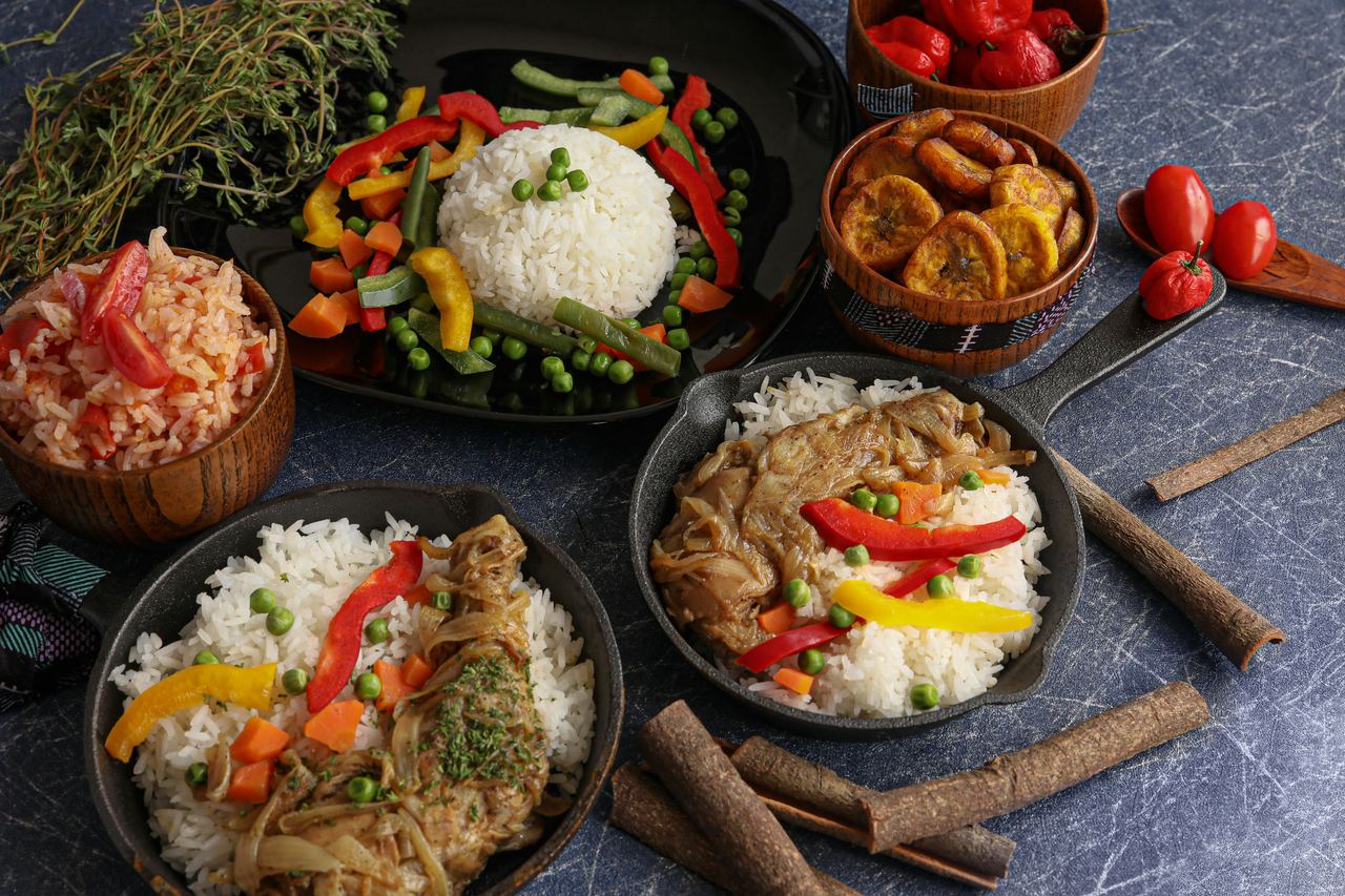 Table dressée avec riz, poulet yassa, légumes et plantains